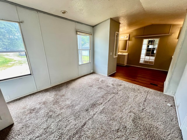 unfurnished bedroom with dark carpet, a textured ceiling, and vaulted ceiling