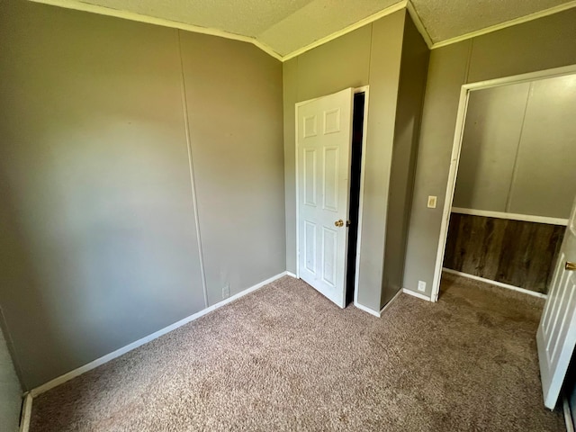 unfurnished bedroom with lofted ceiling, carpet flooring, ornamental molding, and a textured ceiling