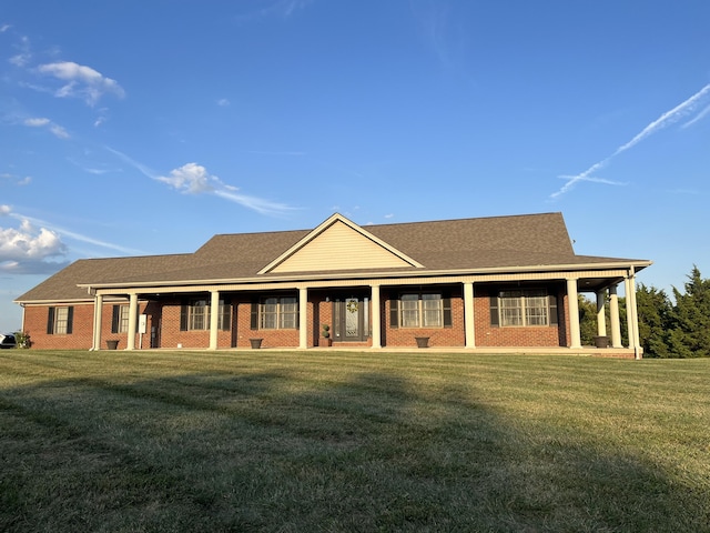 view of front of property featuring covered porch, a front lawn, and brick siding