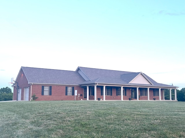 view of front facade with a garage, covered porch, brick siding, and a front lawn