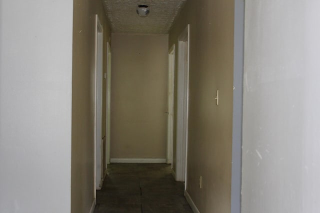 corridor featuring a textured ceiling and dark tile patterned floors