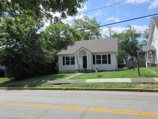 view of front facade featuring a front yard, a chimney, roof with shingles, and crawl space