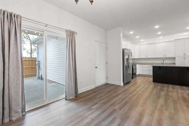 kitchen with appliances with stainless steel finishes, light hardwood / wood-style floors, white cabinetry, and sink