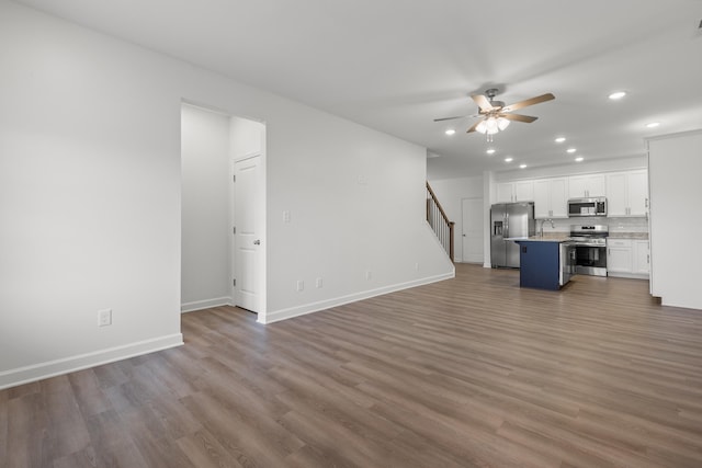 unfurnished living room featuring ceiling fan, sink, and hardwood / wood-style flooring