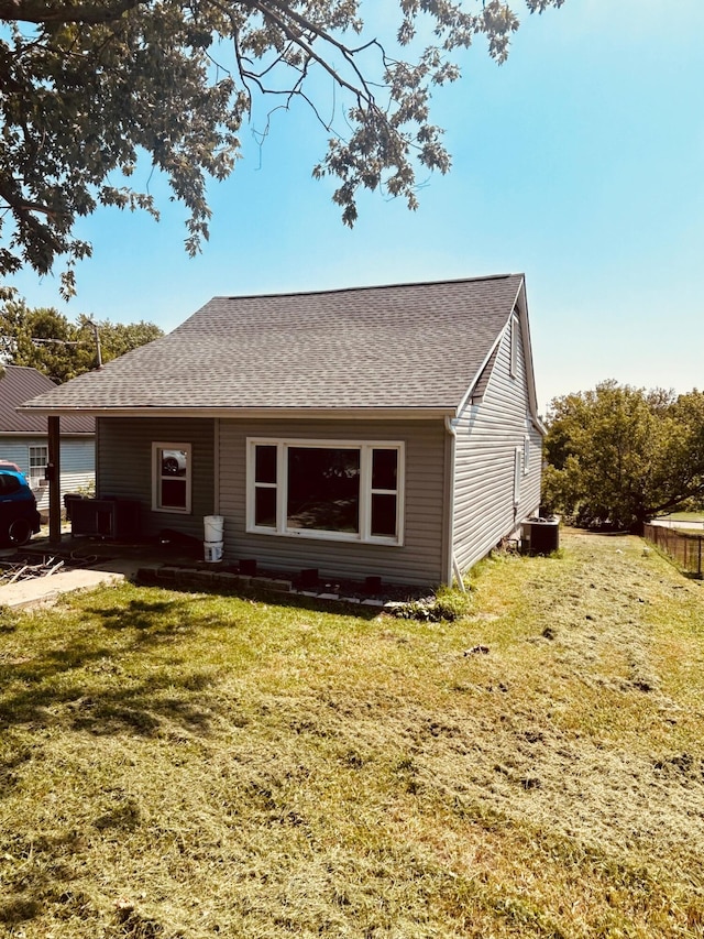 back of house with central air condition unit and a yard