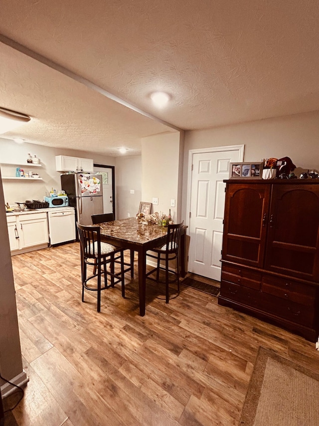 dining space featuring light hardwood / wood-style floors and a textured ceiling