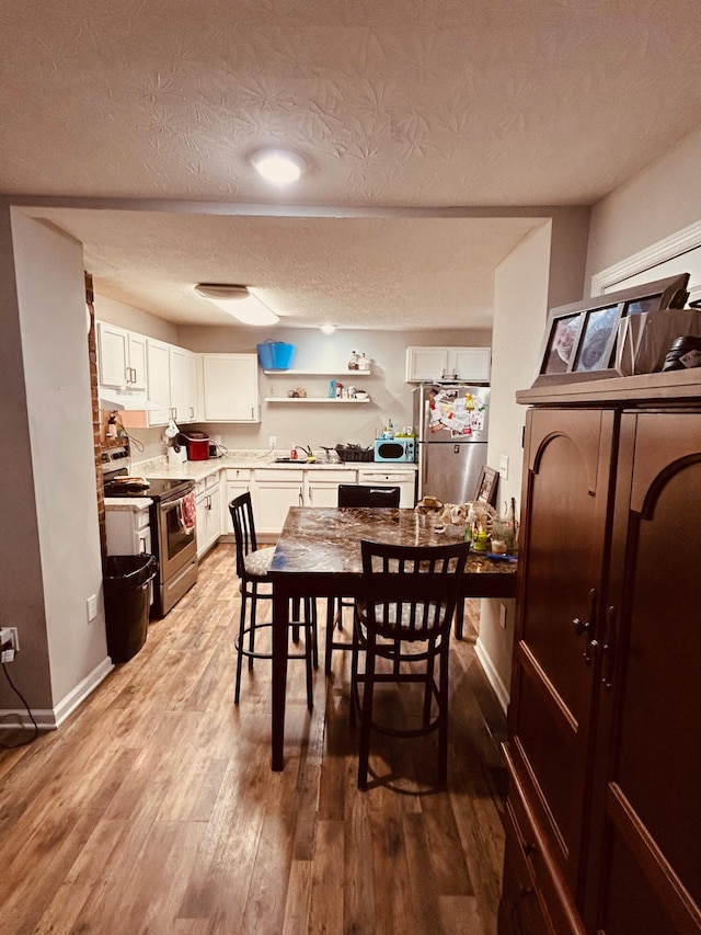 dining area with sink, hardwood / wood-style floors, and a textured ceiling