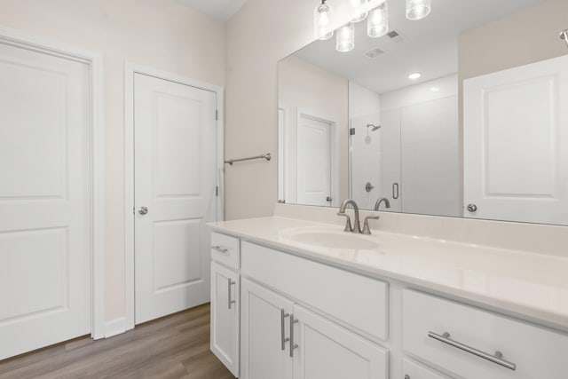 bathroom with hardwood / wood-style flooring, a shower with door, and vanity