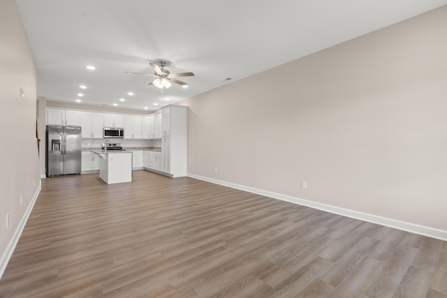 unfurnished living room featuring light wood-type flooring and ceiling fan