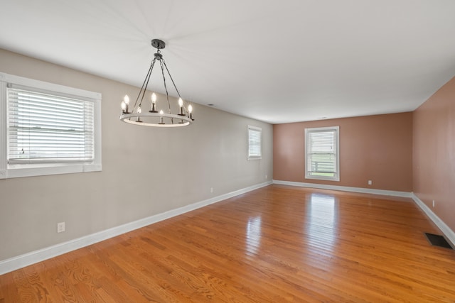 spare room with light hardwood / wood-style flooring and a chandelier