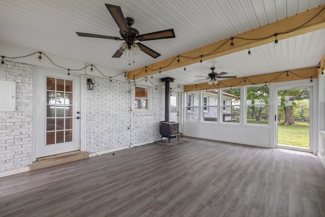 unfurnished sunroom with ceiling fan, wooden ceiling, and a wood stove