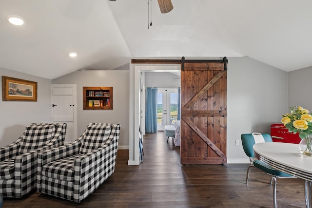 living room featuring ceiling fan, vaulted ceiling, dark hardwood / wood-style floors, and a barn door