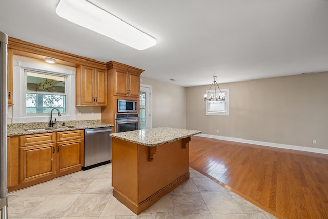 kitchen with light tile patterned flooring, a kitchen breakfast bar, sink, decorative light fixtures, and stainless steel appliances