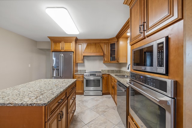 kitchen with a kitchen island, custom exhaust hood, appliances with stainless steel finishes, light tile patterned floors, and sink