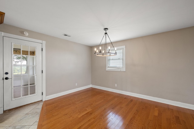 unfurnished room with a wealth of natural light, light hardwood / wood-style flooring, and a chandelier