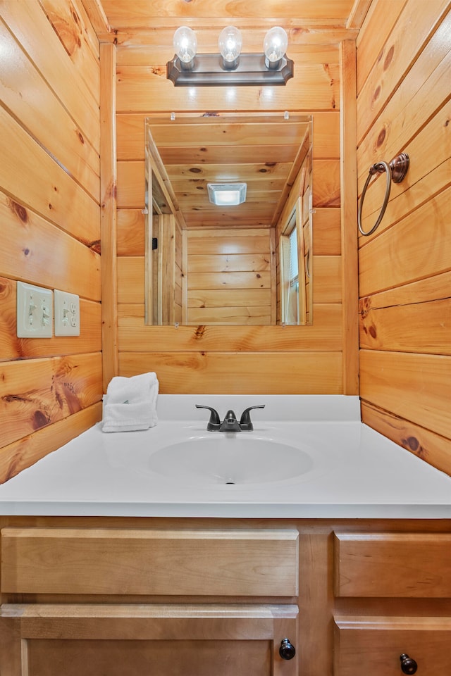 bathroom with wood walls, wooden ceiling, and vanity