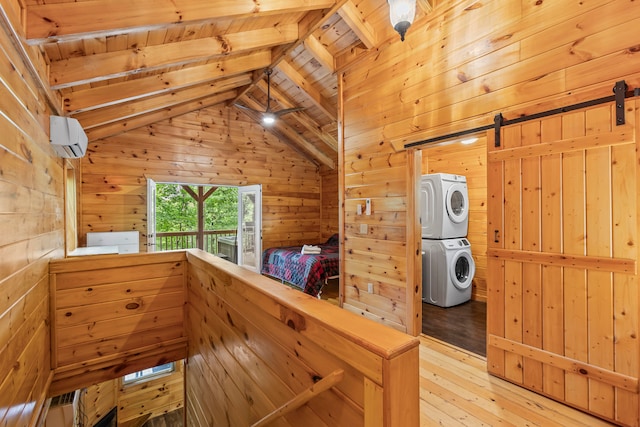 interior space featuring stacked washer and dryer, wooden walls, hardwood / wood-style flooring, and a barn door