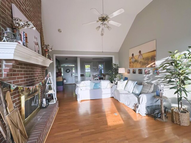 unfurnished living room with ceiling fan, high vaulted ceiling, hardwood / wood-style floors, and a fireplace