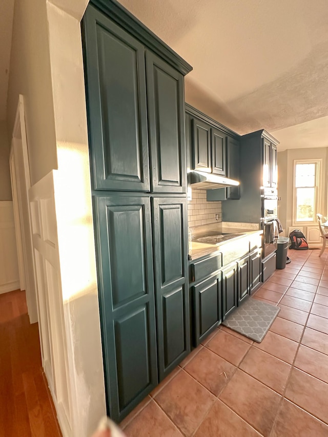 kitchen with stovetop, backsplash, light wood-type flooring, and stainless steel double oven