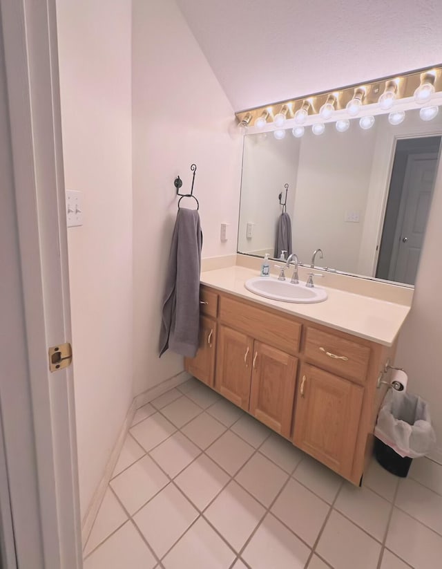 bathroom with tile patterned flooring, vaulted ceiling, and vanity