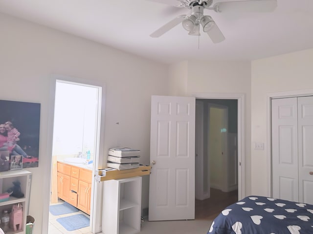 tiled bedroom with ceiling fan, sink, a closet, and ensuite bath