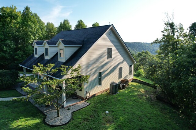 view of property exterior with cooling unit and a lawn