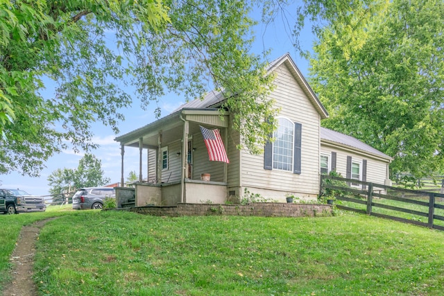 view of side of property featuring covered porch and a lawn