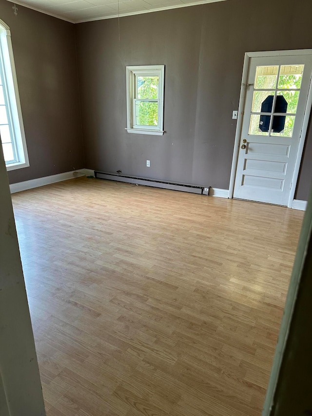 spare room featuring light hardwood / wood-style flooring, a baseboard radiator, and plenty of natural light