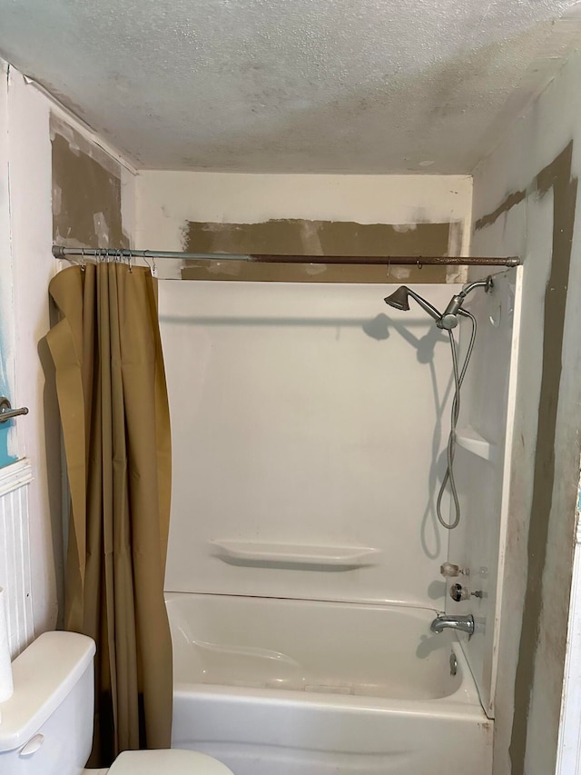 bathroom featuring toilet, a textured ceiling, and shower / tub combo