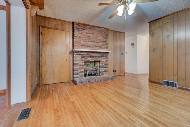 kitchen with black appliances, light hardwood / wood-style floors, and wood walls