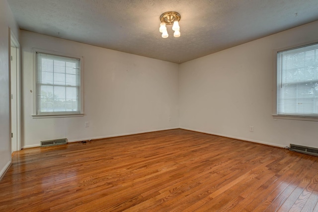 spare room featuring light hardwood / wood-style floors and a textured ceiling