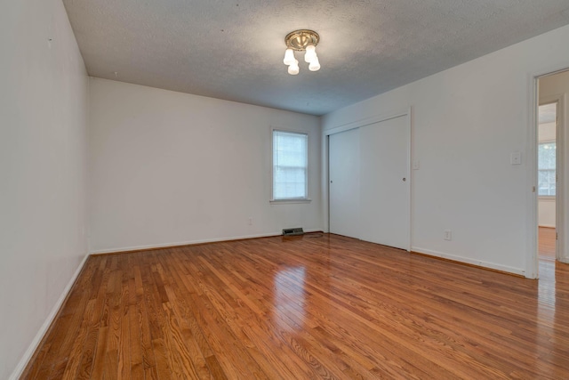 unfurnished room with a healthy amount of sunlight, a textured ceiling, and hardwood / wood-style flooring