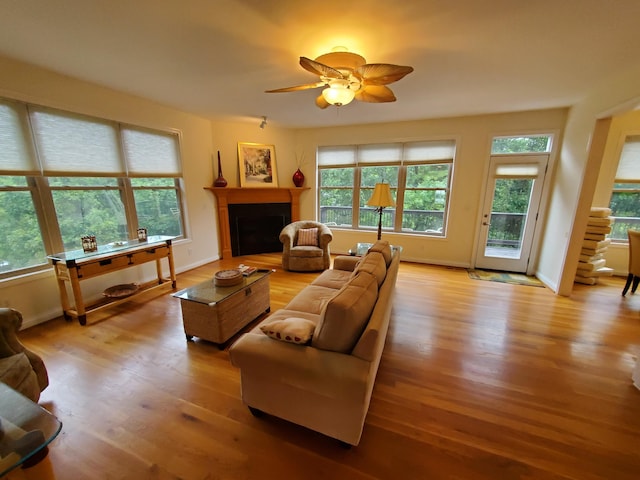 living room with light wood-style flooring, a fireplace, and baseboards