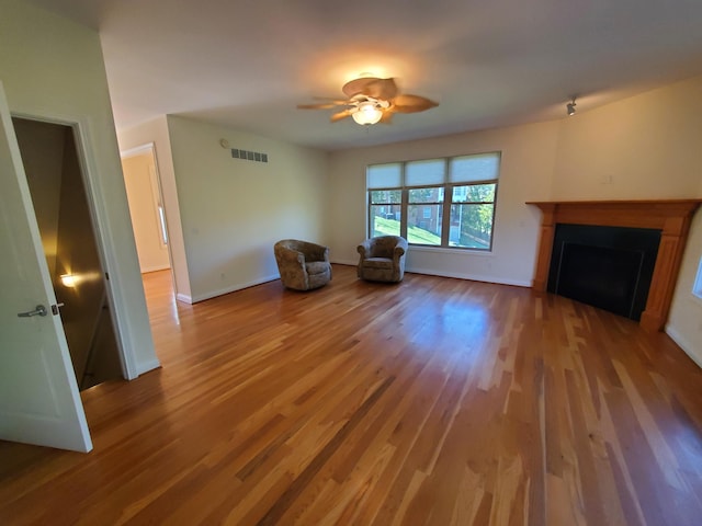 unfurnished room with a fireplace, wood finished floors, visible vents, and baseboards