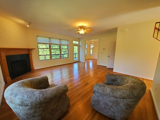 living room with ceiling fan, a fireplace, wood finished floors, and baseboards