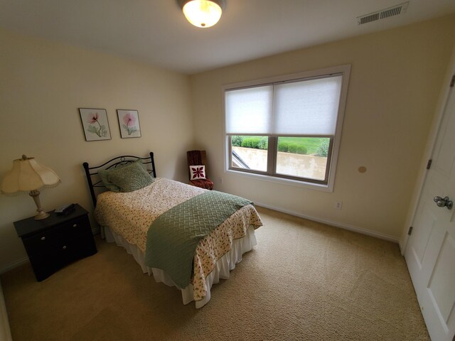 bedroom featuring visible vents, light carpet, and baseboards