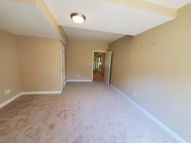 unfurnished room featuring light carpet and baseboards