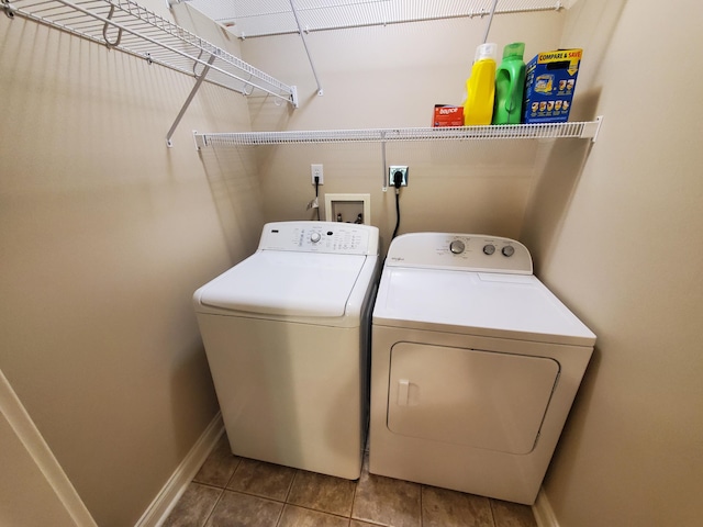 clothes washing area featuring laundry area, baseboards, washing machine and clothes dryer, and light tile patterned floors