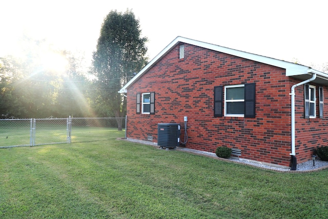 view of side of home featuring central air condition unit and a yard