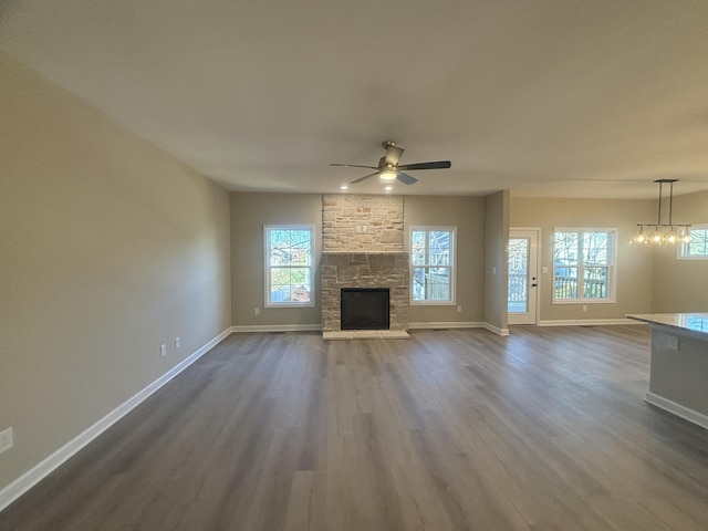 unfurnished living room with hardwood / wood-style flooring, a fireplace, and ceiling fan with notable chandelier