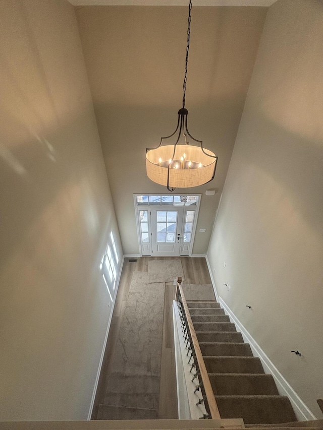 staircase with hardwood / wood-style floors, a towering ceiling, and a healthy amount of sunlight