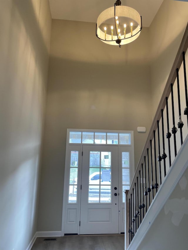 entryway featuring a towering ceiling and a chandelier