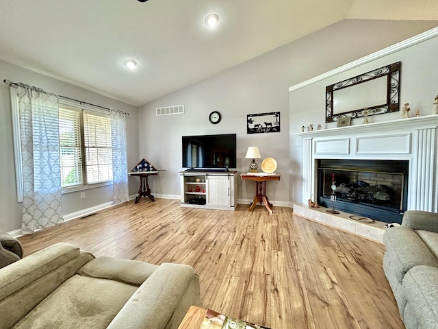 living room featuring light wood-type flooring, lofted ceiling, and a fireplace