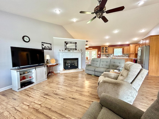 living room with light hardwood / wood-style floors, lofted ceiling, and ceiling fan