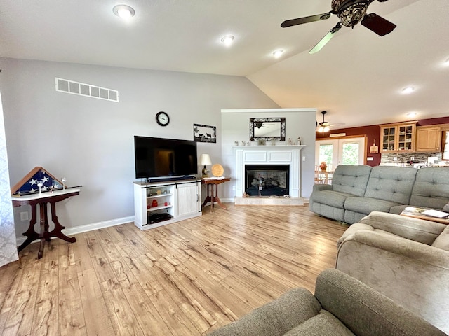 living room featuring ceiling fan, light hardwood / wood-style floors, and vaulted ceiling