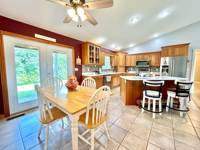 kitchen with vaulted ceiling, appliances with stainless steel finishes, a center island, and a wealth of natural light