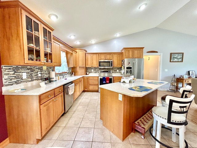 kitchen featuring lofted ceiling, a kitchen island, stainless steel appliances, and light tile patterned floors