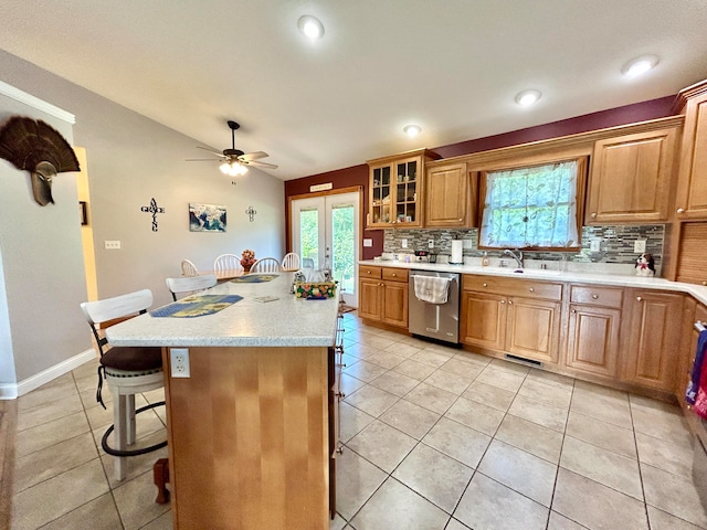 kitchen featuring a center island with sink, a wealth of natural light, a breakfast bar, dishwasher, and decorative backsplash