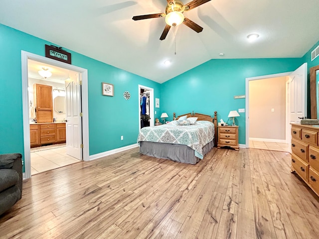 bedroom with ceiling fan, light wood-type flooring, connected bathroom, and lofted ceiling