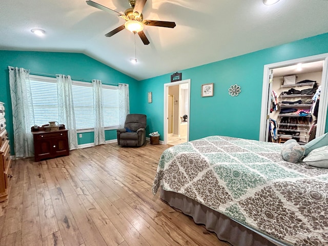 bedroom featuring light wood-type flooring, lofted ceiling, ceiling fan, and a spacious closet